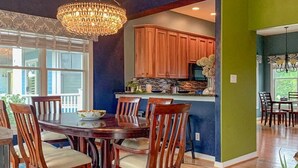 A dining area with a wooden table and chairs, a chandelier, and a view of the kitchen. - Everyday Your Beachside Escape! (Cape Charles)