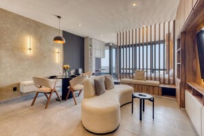 A modern living room with a round sofa, a dining table with chairs, and a large window with a view.