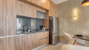 A modern kitchen with wood paneling, stainless steel appliances, and a dining area with a table and chairs. - Sleek Reforma Studio · Pool, Gym & Skyline (Ciudad de México)