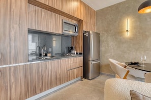A modern kitchen with wood paneling, stainless steel appliances, and a dining area with a table and chairs. - Sleek Reforma Studio · Pool, Gym & Skyline (Ciudad de México)