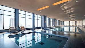 A large indoor swimming pool with clear glass walls, allowing views of the cityscape. - Sleek Reforma Studio · Pool, Gym & Skyline (Ciudad de México)