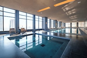 A large indoor swimming pool with clear glass walls, allowing views of the cityscape. - Sleek Reforma Studio · Pool, Gym & Skyline (Ciudad de México)