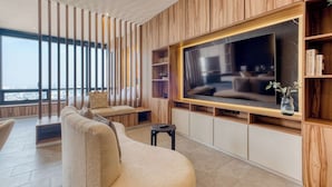 A modern living room with a large TV, wooden paneling, and a view of the city. - Sleek Reforma Studio · Pool, Gym & Skyline (Ciudad de México)