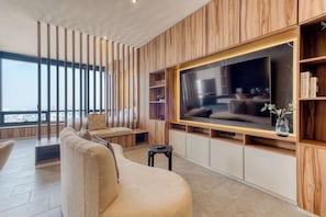 A modern living room with a large TV, wooden paneling, and a view of the city. - Sleek Reforma Studio · Pool, Gym & Skyline (Ciudad de México)
