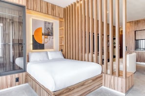 A modern bedroom with a bed, a wooden partition, and a large abstract painting.