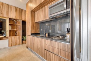 A modern kitchen with wooden cabinetry, stainless steel appliances, and a granite countertop.