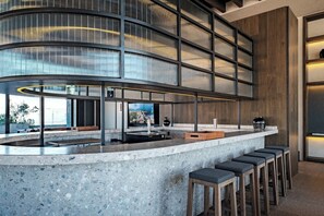 A modern bar area with a curved counter, bar stools, and a large window. - Reforma Studio · Pool, Gym & Revolución Views (Ciudad de México)