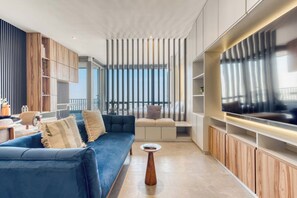 A modern living room with a blue sofa, wooden cabinets, and a large flat-screen TV.
