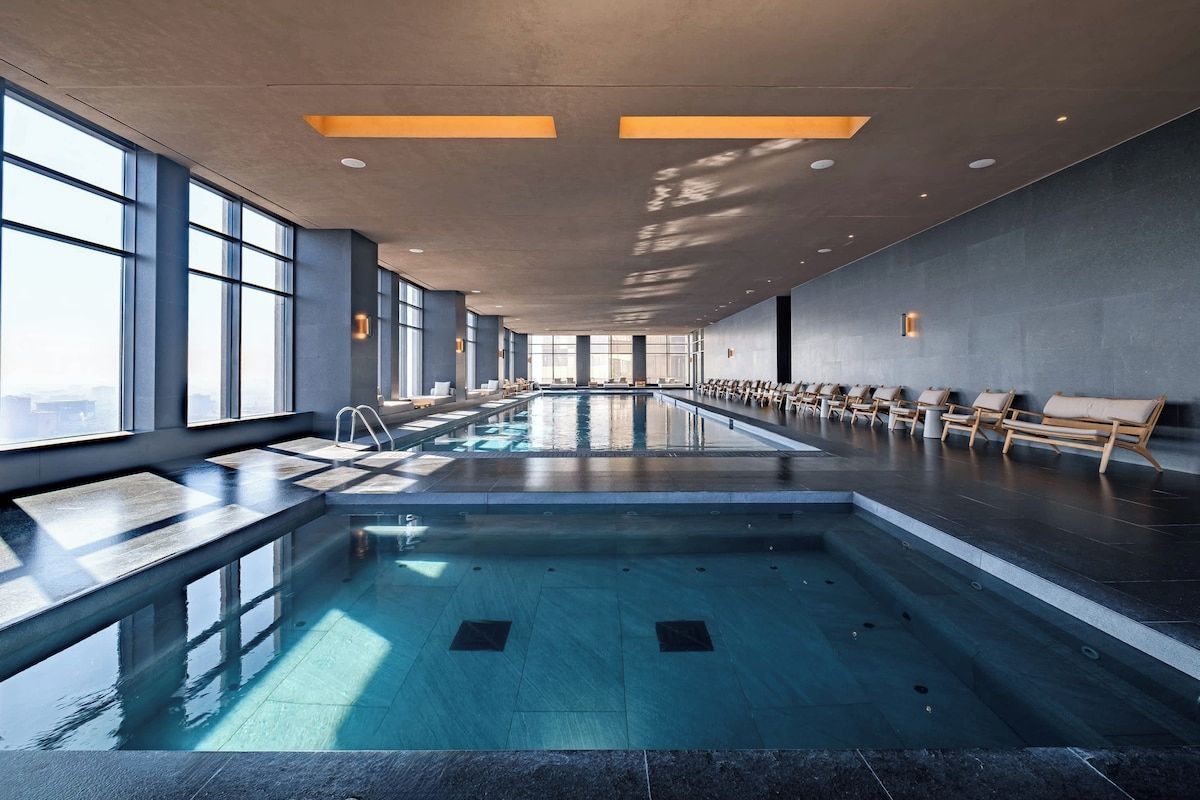 Ein großes Hallenbad mit einer langen Sitzbank entlang einer Seite und einer von der Sonne durchfluteten Decke.
