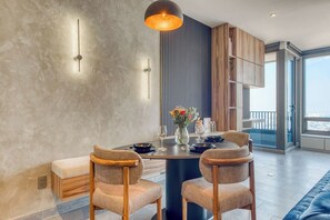 A dining area with a round table, two chairs, a vase with flowers, and a pendant light. - Reforma Studio · Pool, Gym & Revolución Views (Ciudad de México)