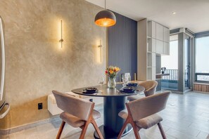 Un espace de salle à manger moderne avec une table ronde, des chaises et un luminaire suspendu.