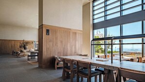 Ruime binnenzone met een grote tafel en stoelen, een houten accentmuur en grote ramen met uitzicht.