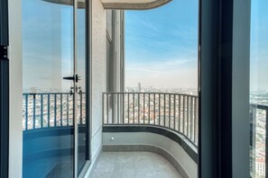 A balcony with a glass door leading to a cityscape view.