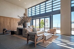 A spacious living area with a large window, a sofa set, a coffee table, and a potted plant.