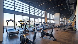 Een fitnessruimte met loopbanden, hometrainers en roeimachines.
