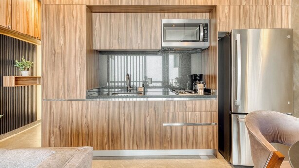 Een moderne keuken met houten kastjes, een roestvrijstalen koelkast en een magnetron.
