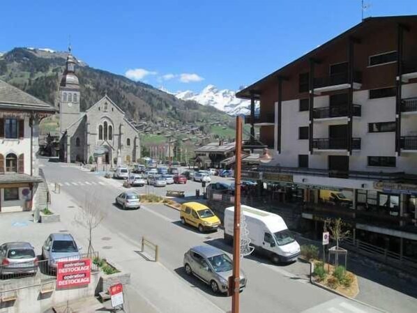 Vista callejera con una iglesia, una montaña al fondo y una mezcla de coches y edificios.