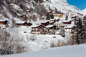A snow-covered mountain village with wooden houses and a ski slope.