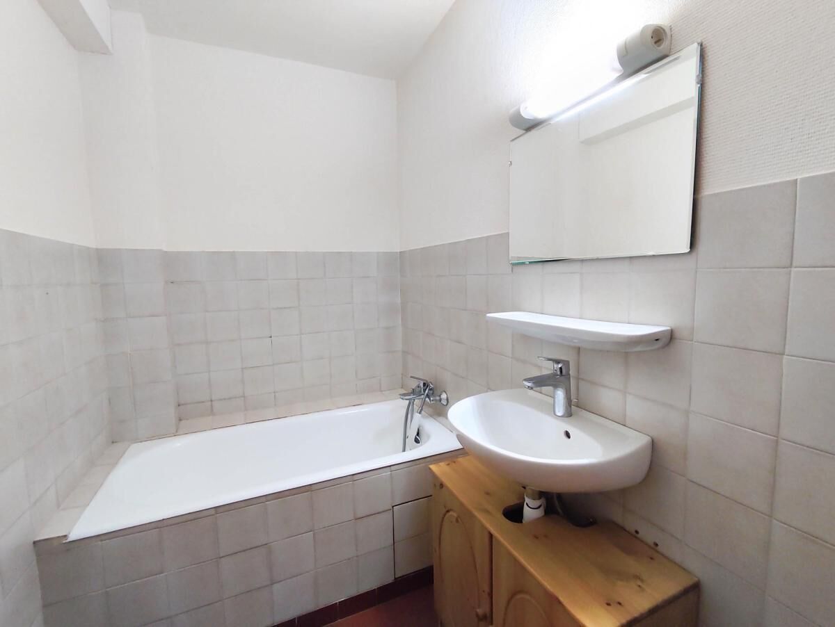 A bathroom with a bathtub, a sink, and a mirror.