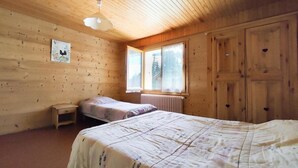 Puuinen mökkimäinen huone, jossa on sänky, pieni pöytä ja ikkuna.