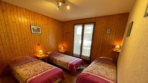 Ein Zimmer mit Holzwänden, zwei Betten mit rosa Bettwäsche, einem Fenster mit Vorhängen und einer Deckenleuchte.