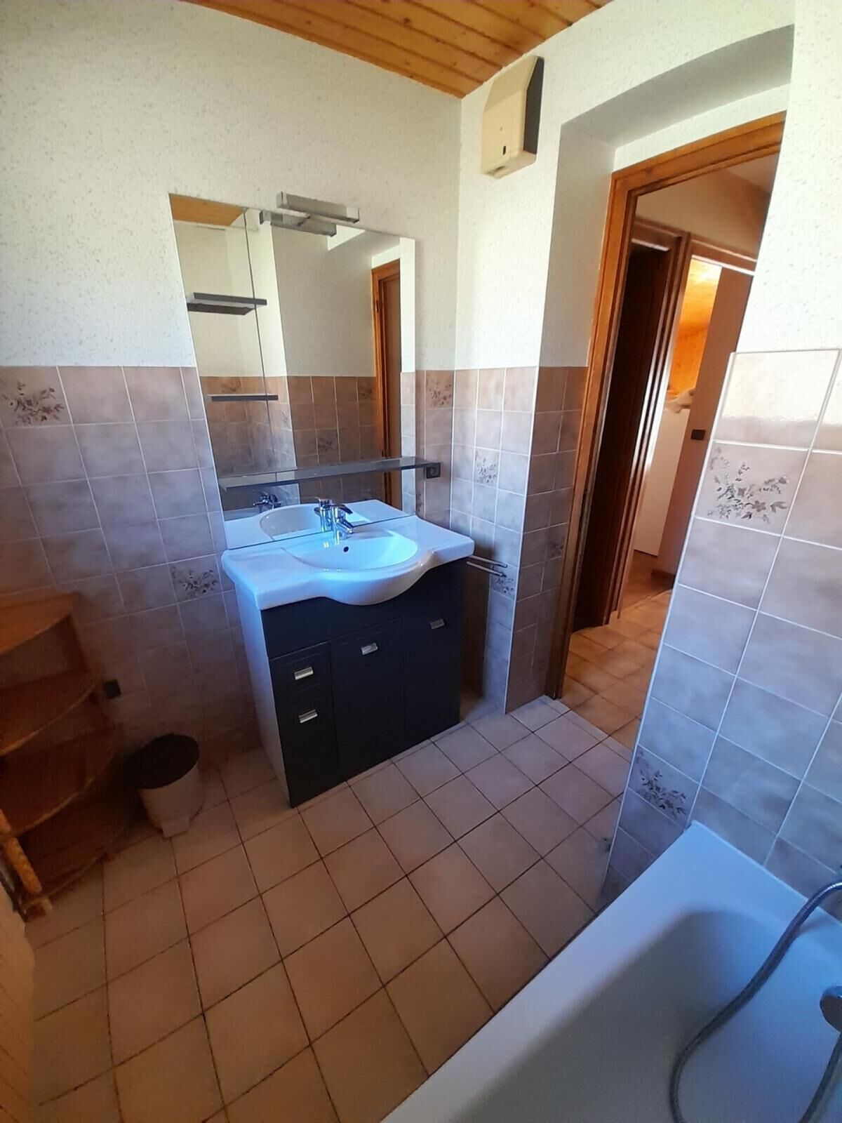 Een badkamer met wastafel, spiegel en bad.