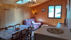 A cozy cabin with a dining table, chairs, a sofa, and a small kitchen area. - 2nd floor, balcony, parking, ski locker, 51m², Le Grand Bornand (Le Grand-Bornand)