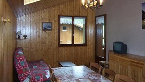 A wooden cabin interior with a dining table, chairs, a bench, a television, and a window. - 2nd floor, balcony, parking, ski locker, 51m², Le Grand Bornand (Le Grand-Bornand)