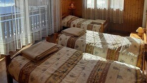 A room with two beds, wooden walls, and large windows with curtains. - 1st floor, balcony, fireplace or stove, parking, ski locker, 52m², Le Grand Bornand (Le Grand-Bornand)