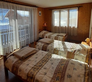 Ein Zimmer mit zwei Betten, Holzwänden und großen Fenstern mit Vorhängen.