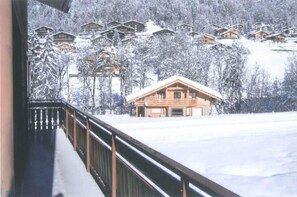 Een besneeuwd landschap met houten huisjes en een chalet op de voorgrond.