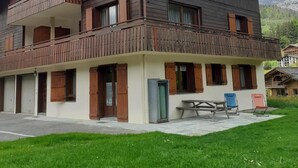 Een gebouw met twee verdiepingen, een balkon op de bovenverdieping, een overdekt terras en uitzicht op de bergen.