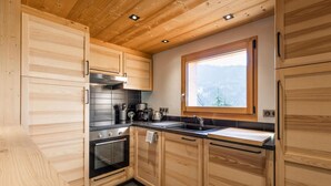 Une cuisine moderne avec des meubles en bois, un four en acier inoxydable et une fenêtre donnant sur l’extérieur.