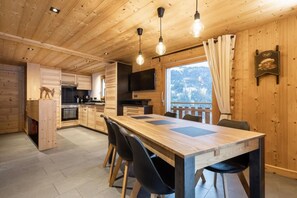 Un interno in legno con zona pranzo, cucina e una finestra vista su un paesaggio innevato.