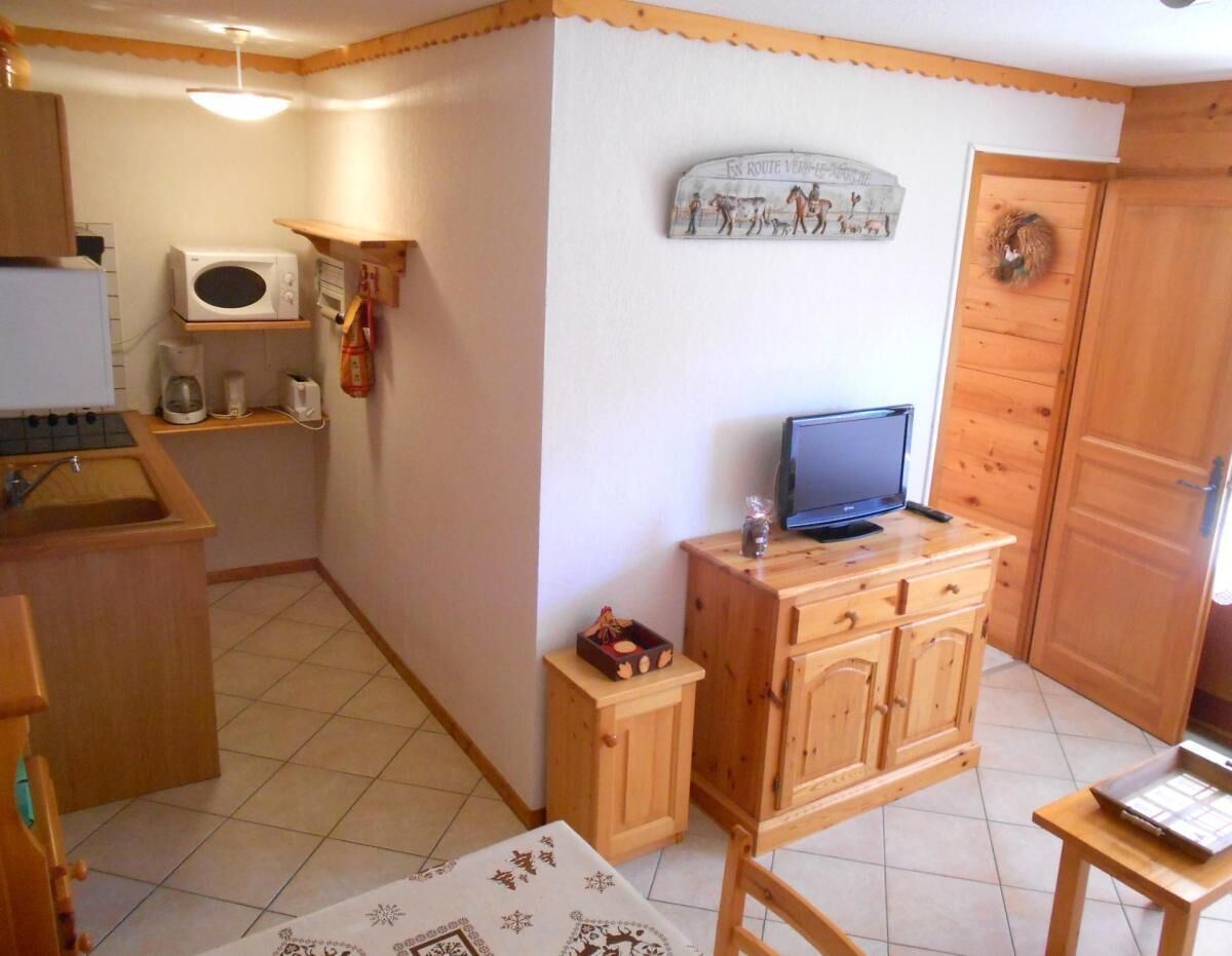 A compact kitchen with a microwave, coffee maker, and wooden cabinets.