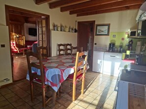 A dining area with a table set for four, wooden chairs, a kitchen area with appliances, and a television mounted on the wall. - Wifi, 3rd floor, view mountain, balcony, parking, tv, ski locker, 102m², Le Grand Bornand (Le Grand-Bornand)