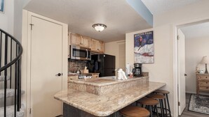 A kitchen with a granite countertop, a refrigerator, and wooden cabinets. - Wonderful 2 bedroom, pet friendly, ski-in/ski-out (Granby)