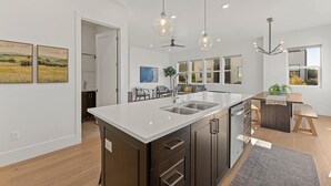 A modern kitchen with a large island, pendant lighting, and a view to the dining area. - Villa #19 at Bloomington Country Club: Pool, Golf, Restaurant (St. George)