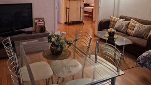 A living room with a TV, a dining table with chairs, a sofa, and a lamp. - Le Grand Robinson, 6 minutes from RER B Robinson, ideal for families. (Le Plessis-Robinson)