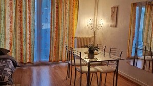 A dining area with a glass table and chairs, a sofa, and curtains with a floral pattern. - Le Grand Robinson, 6 minutes from RER B Robinson, ideal for families. (Le Plessis-Robinson)