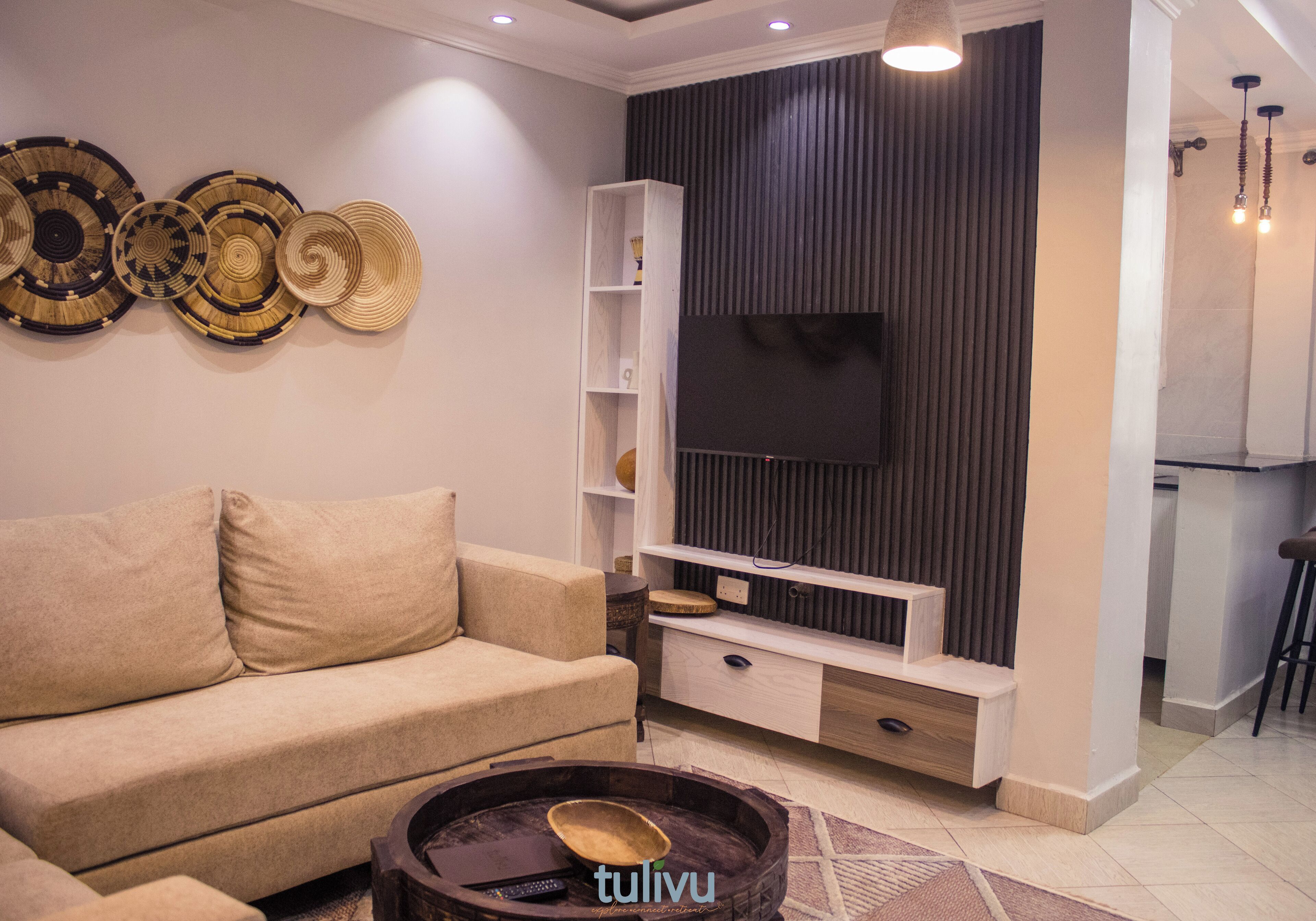 Een moderne woonkamer met een bank, salontafel, televisie en decoratieve wandkunst.
