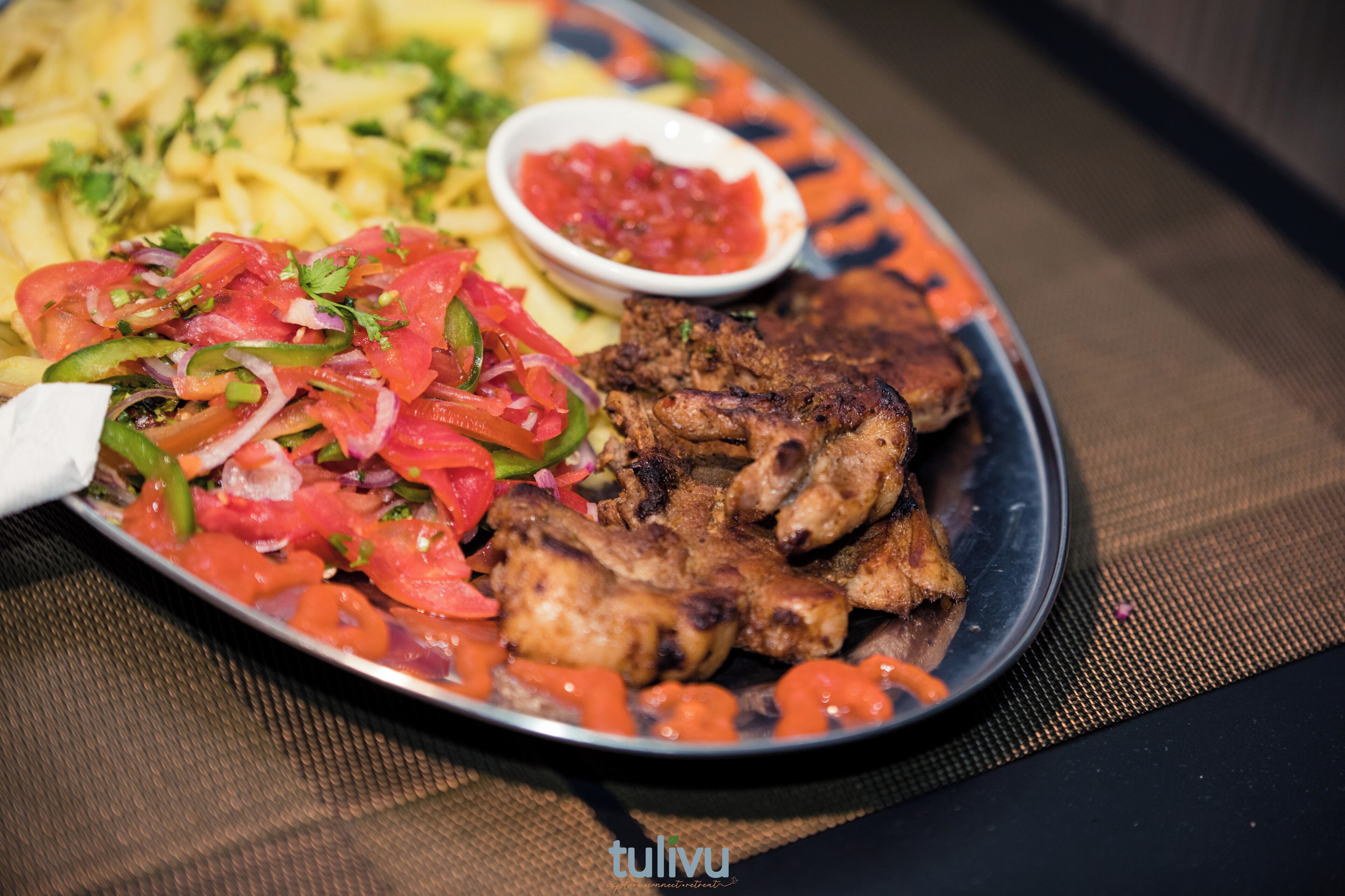 A plate of food with grilled meat, vegetables, and a side of fries.
