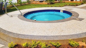 Ein kreisförmiger Pool mit blauer Innenauskleidung, umgeben von einem Deck mit Kieselmuster.
