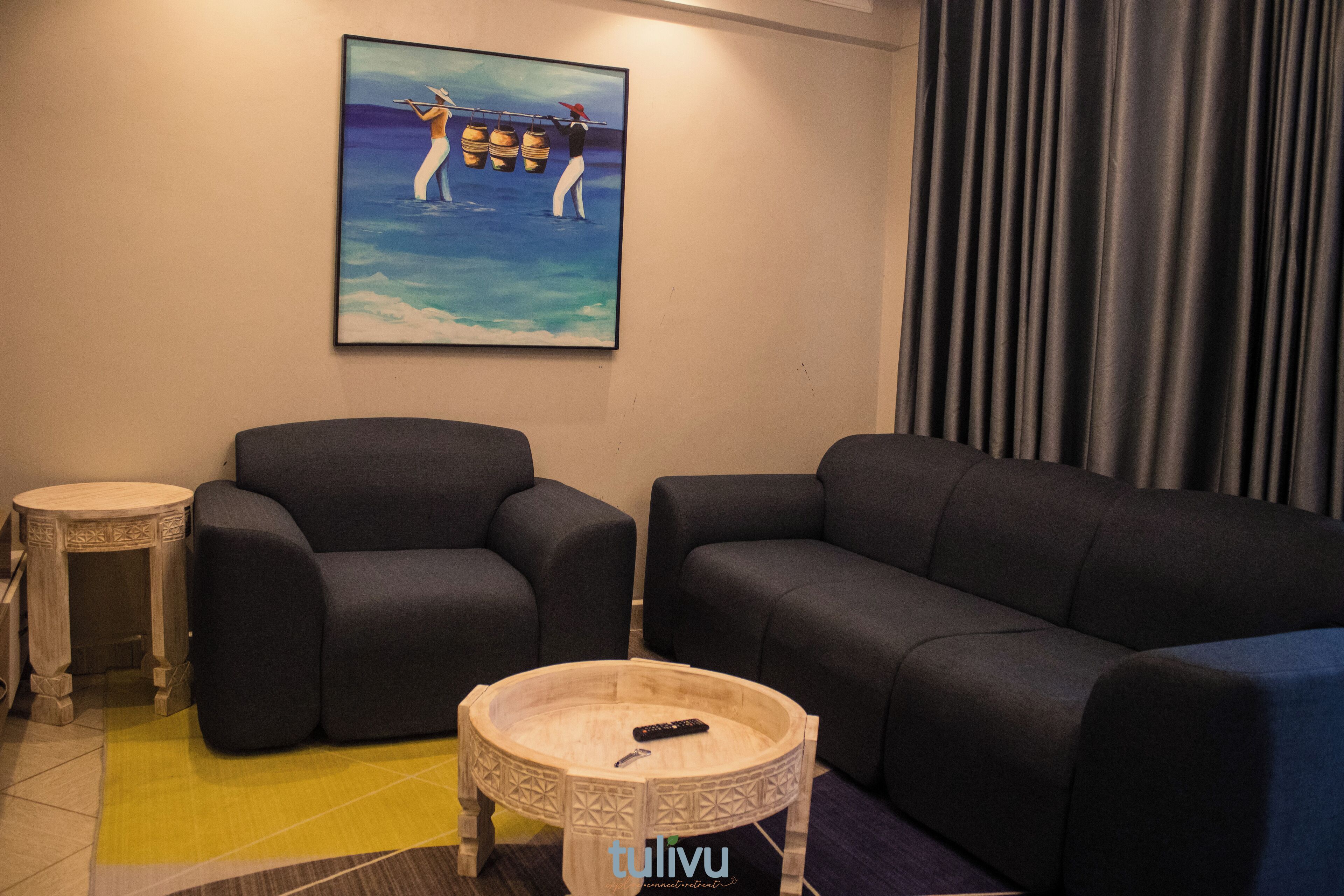 A living room with two dark sofas, a small round coffee table, and a painting on the wall.