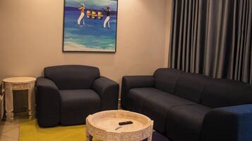 A living room with two dark sofas, a small round coffee table, and a painting on the wall.