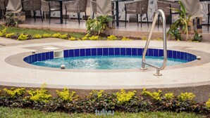 Ein Swimmingpool mit blauer Fliesenbordur, umgeben von einer Betonplattform und einer Metallleiter.