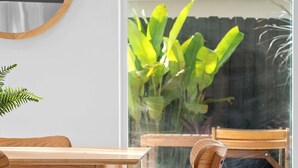 A wooden dining table and chairs inside a room with a large window. - Spacious, Bright Condo-Victoria Park Near Beach (Fort Lauderdale)