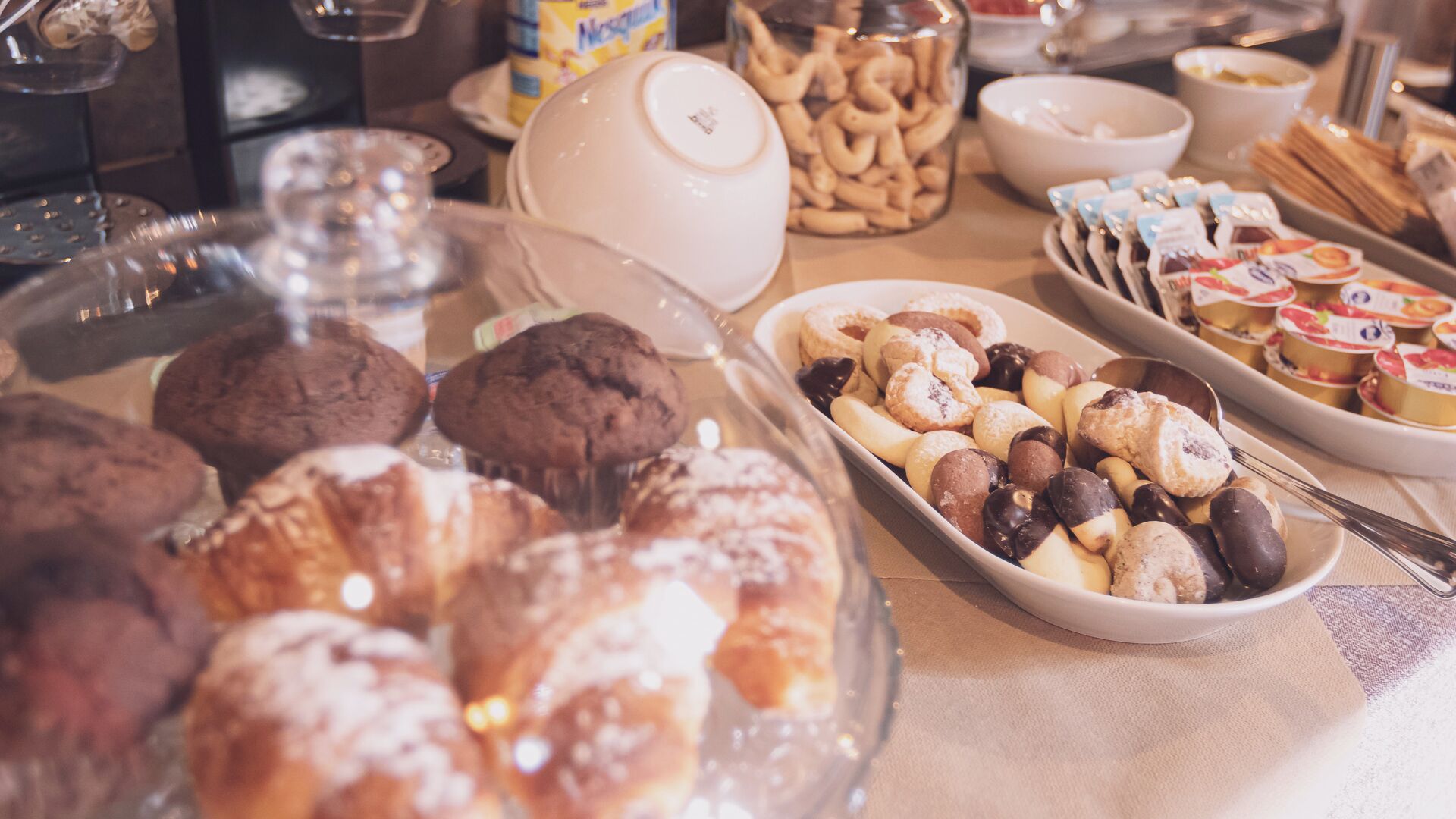Um buffet com diversos doces e sobremesas, incluindo biscoitos, muffins e tortas de fruta.