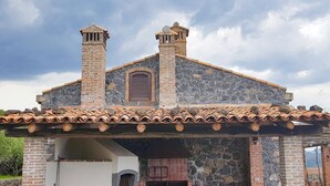 A stone building with two chimneys, a tiled roof, and a stone fireplace. - LA GELSOMINA (Mascali)