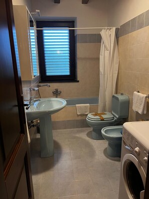 A bathroom with a sink, toilet, bidet, bathtub, and a washing machine. - LA GELSOMINA (Mascali)